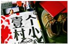 贴着壹个村小红色手印标识的白纸，旁边放着笔记本与鞋子